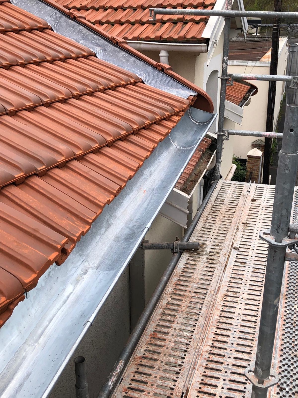 Gouttière en zinc rénovée le long d’une couverture en tuiles